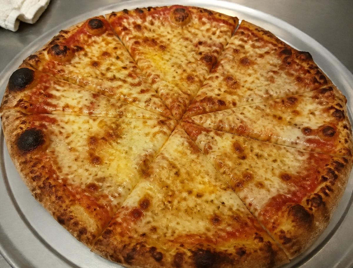 Frisch gebackene Pizza mit goldenem Gouda, in Stücke geschnitten auf dem Blech